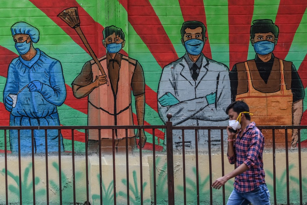 A man speaks on a mobile phone walking past a wall mural depicting frontline Covid-19 warriors from various professions in Mumbai in March. A World Economic Forum report found that individuals and communities most negatively affected by Covid-19 “are likely to be those that are already most disadvantaged”, deepening existing inequalities. Photo: AFP