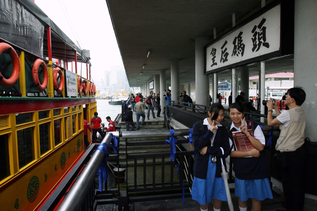 Schoolgirls take photos as a tourist junk berths at Queen’s Pier in April 2007. The pier stopped services after midnight on April 26, 2007, to enable land reclamation in Central, before being demolished. Photo: Robert Ng