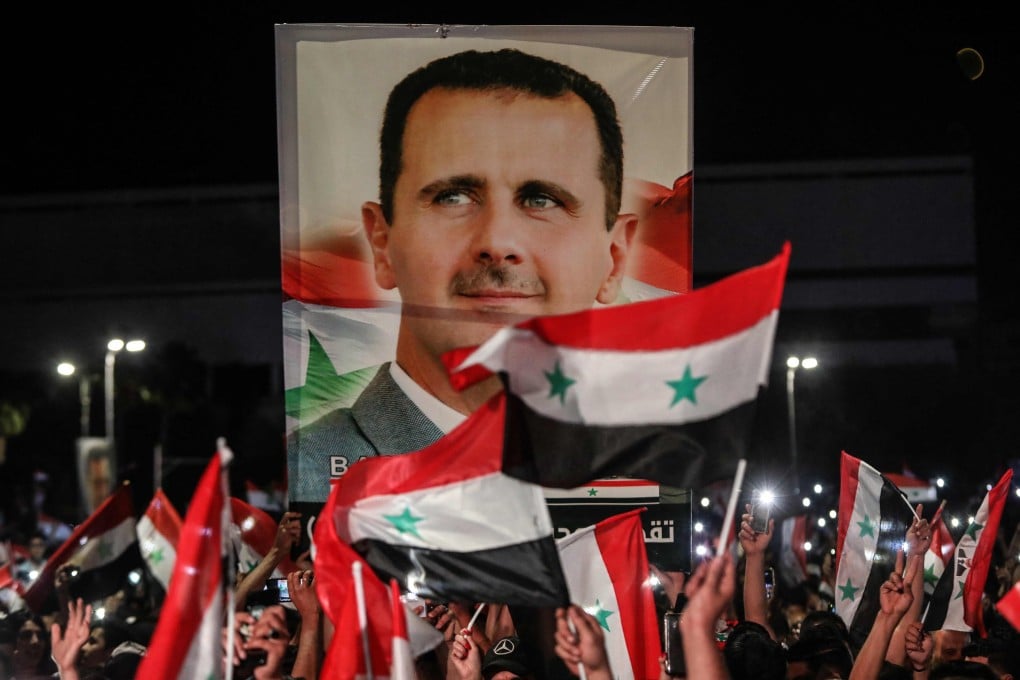 Syrians wave national flags and a large portrait of President Bashar al-Assad as they celebrate in the streets of the capital Damascus on Thursday. Photo: AFP