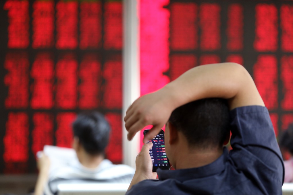 An investor checks stock prices on his mobile phone at a brokerage house in Beijing in June 2018. Photo: Simon Song