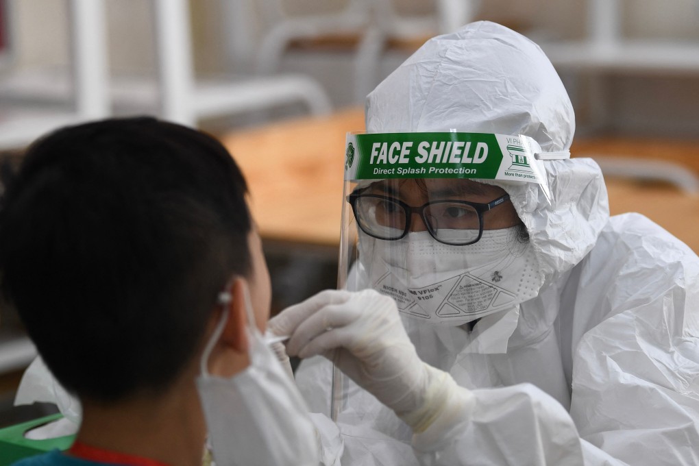 A health worker wearing protective gear takes a swab sample for Covid-19 testing at a school in Hanoi this month. Photo: AFP