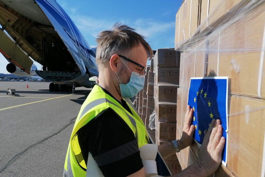 A Red Cross worker sticks an EU flag sticker on a shipment of ventilators from Germany before it is loaded onto a cargo plane bound for New Delhi, India, at Helsinki airport in Finland on May 11. A total of 18 EU member states have pledged medical aid to India. Photo: AFP