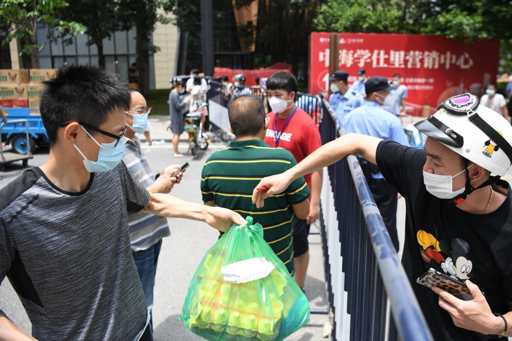 A resident in Guangzhou’s Liwan district collects supplies from a central distribution site amid China’s mini-outbreak of Covid-19. Photo: Xinhua
