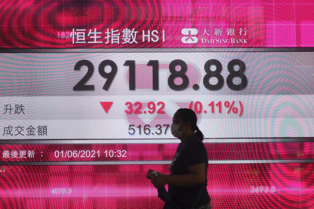 A woman walks past a bank's electronic board showing the Hang Seng Index index on June 1. Photo: AP