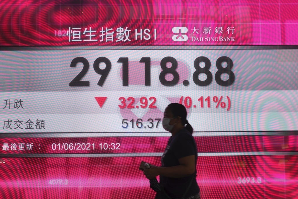 A woman walks past a bank's electronic board showing the Hang Seng Index index on June 1. Photo: AP