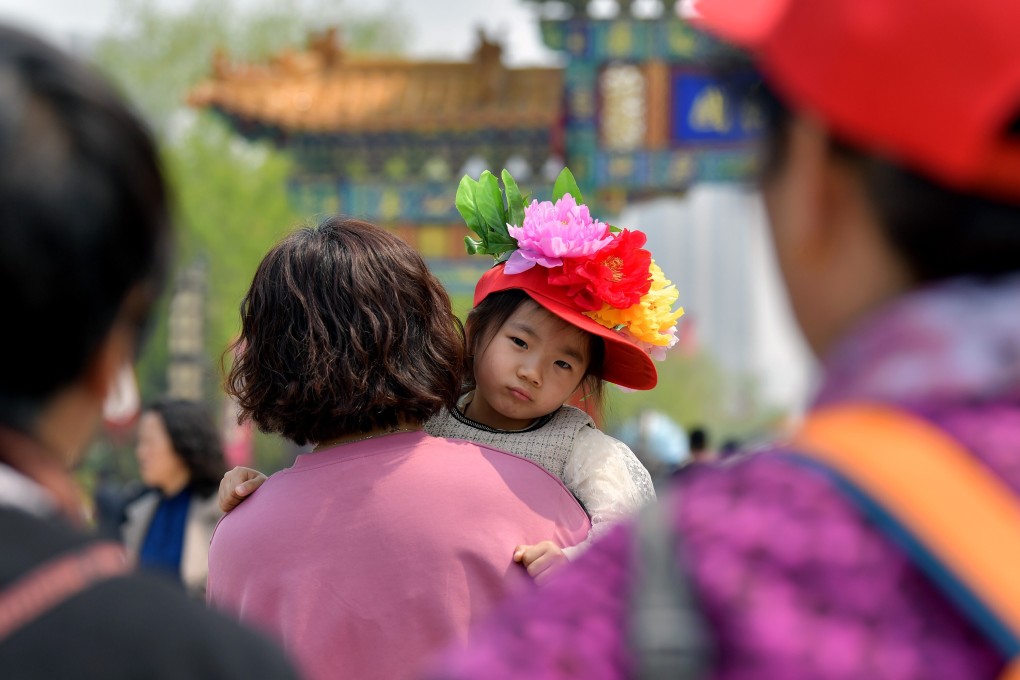 A woman carries a girl as they visit a peony garden in Heze, in east China’s Shandong province, on April 8. In 2020, the country saw only 12 million births, the lowest number in at least six decades. Photo: Xinhua