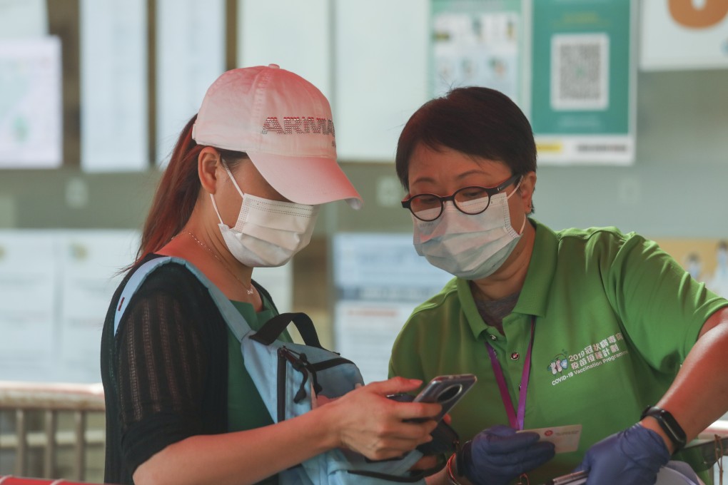 A woman shows a volunteer her vaccine booking at the Central Library in Causeway Bay on May 29. Photo: Xiaomei Chen