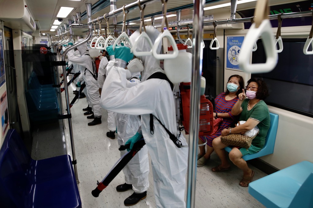 Passengers watch military personnel spray disinfectant on a train in Taipei on May 25. Photo: EPA-EFE