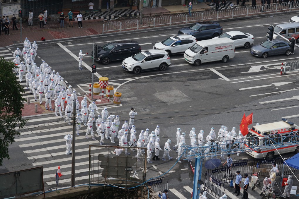 Volunteers in protective gear make their way to a locked down community in Guangzhou’s Liwan district on Thursday to distribute food and supplies. Photo: VCG