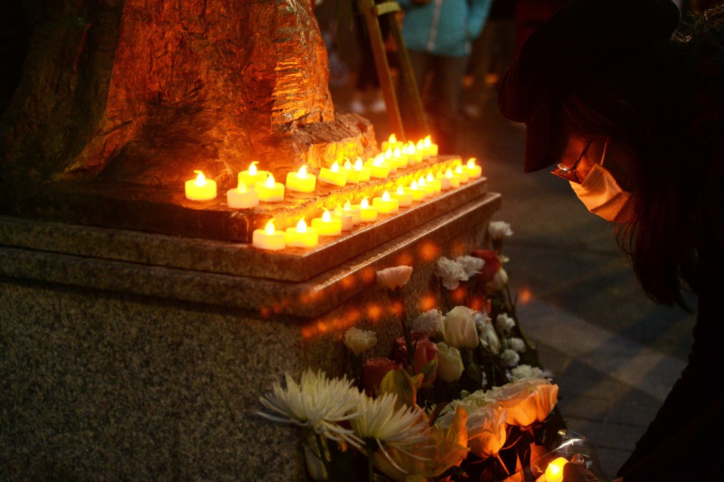 An attendee at the vigil in San Francisco on Thursday night crouches before a replica of the Goddess of Democracy statue. Photo: Owen Churchill