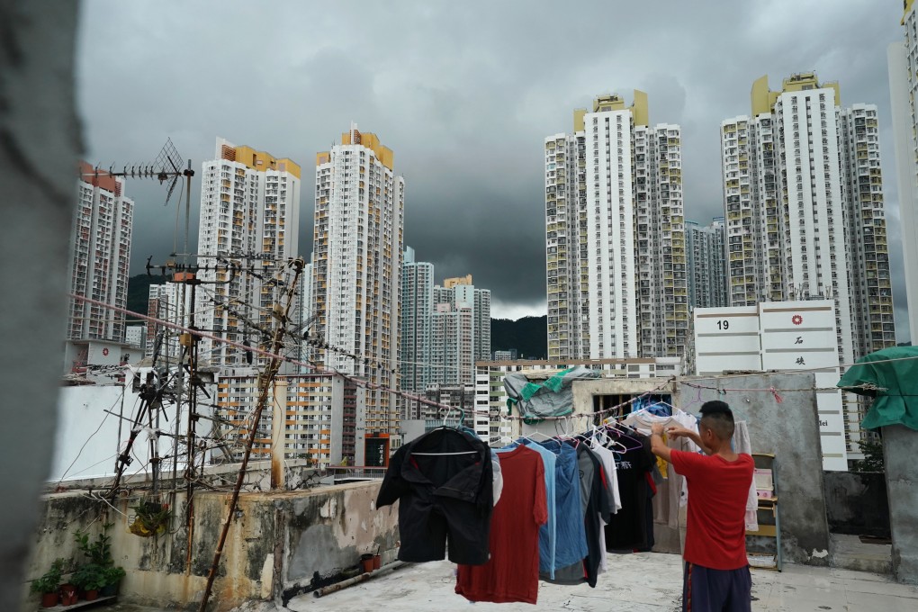 A man hangs his clothes to dry on the rooftop of a building in Sham Shui Po against the backdrop of public housing flats. Photo: Felix Wong