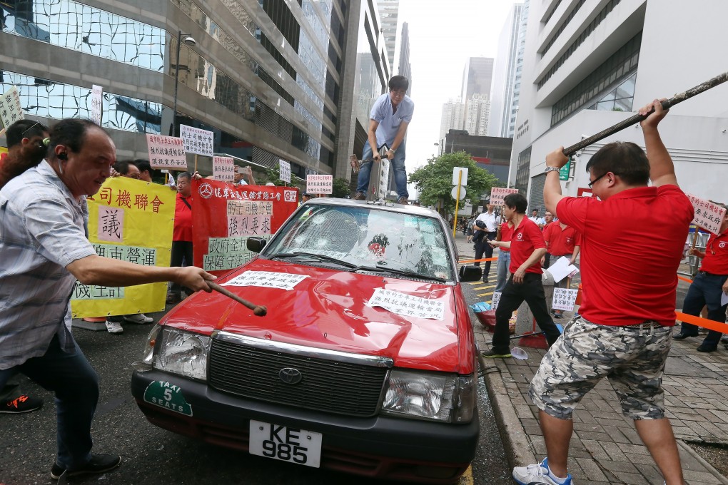 Taxi drivers smash one of their own vehicles as they call on the Hong Kong government to ban ride-hailing services like Uber, in Wan Chai in July 2015. The tussle continues in 2021. Photo: Dickson Lee
