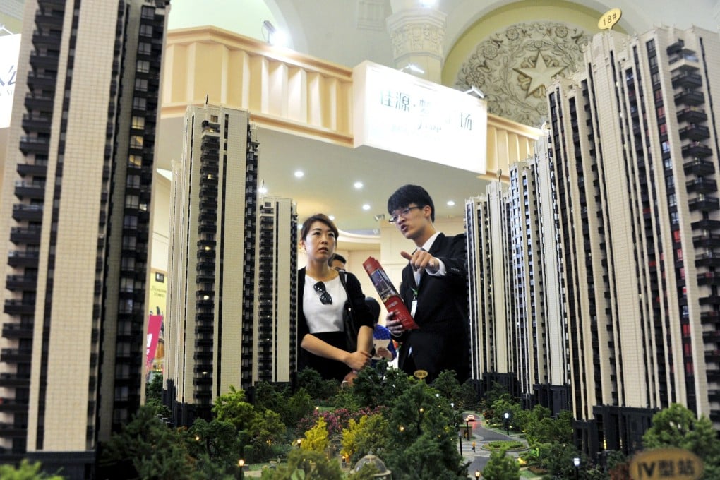 A sales assistant (right) and a customer in front of a model of a residential complex at a real estate exhibition in Shanghai on April 30, 2015. Photo: Reuters.