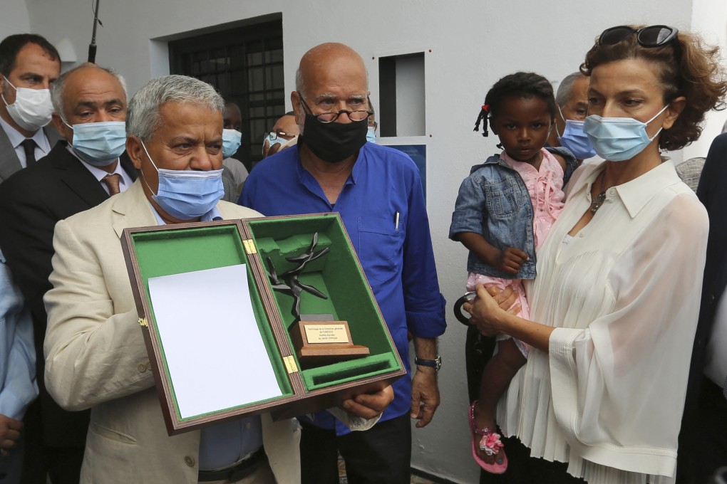 Unesco director general Audrey Azoulay, right, holds a migrant child next to Algerian artist Rachid Koraichi, left, during a visit to the Jardin d’Afrique, a cemetery in southern Tunisia for migrants who drowned crossing the Mediterranean. Photo: AFP