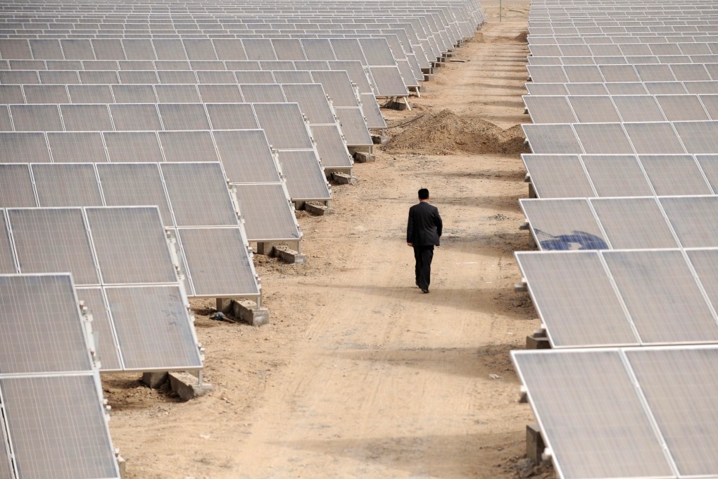 A man walks through solar panels at a solar power plant under construction in Aksu, Xinjiang. File: Reuters