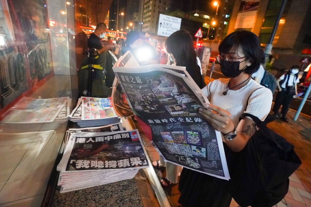 A woman reads the last edition of Apple Daily after queuing at midnight to buy the paper. Photo: Felix Wong