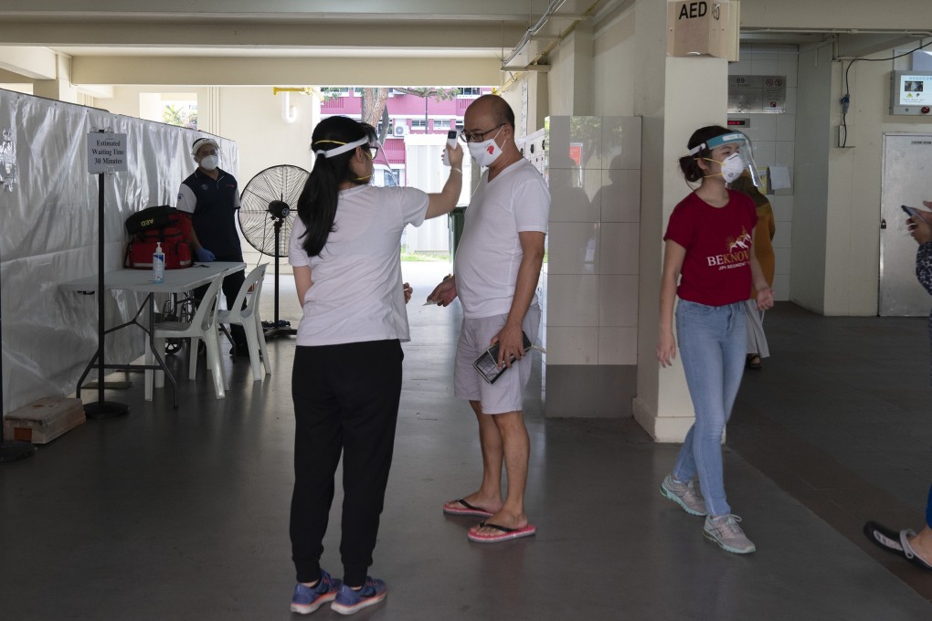 A health care worker checks the temperature of a resident at a mandatory Covid-19 test site set up on a public housing estate in the Redhill area of Singapore on Monday. Photo: Bloomberg