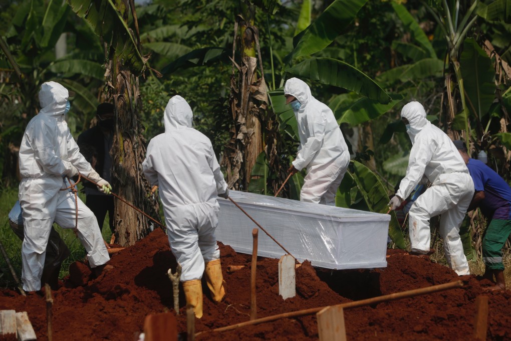 Gravediggers wearing protective gear bury the coffin of a Covid-19 victim at a cemetery in Depok, Indonesia, on Tuesday. Photo: EPA