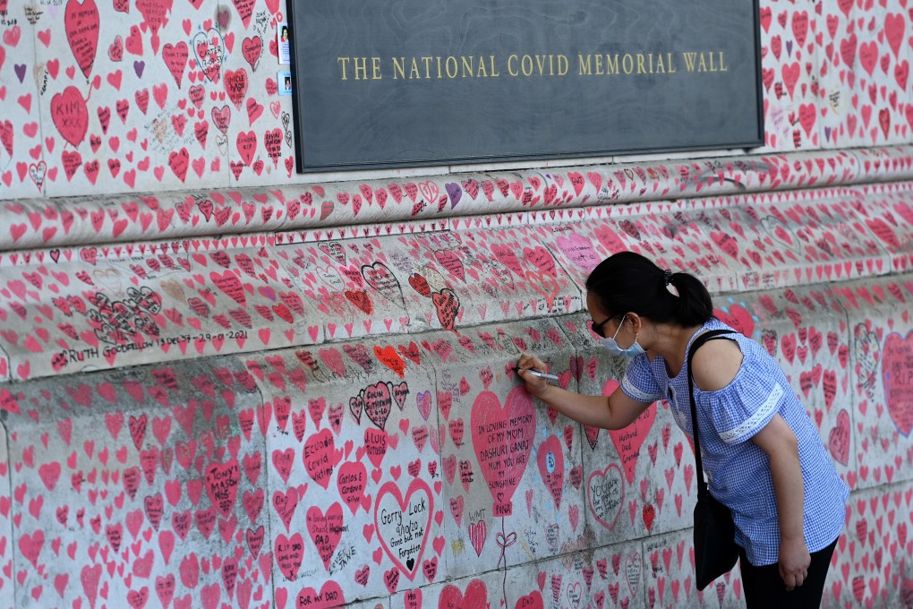 A woman writes a message on the Covid-19 memorial wall in London, Britain. Photo: EPA-EFE