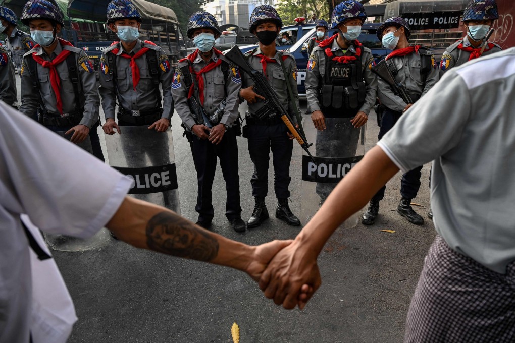 Protesters hold hands in front of police during a demonstration in Yangon. Romances have blossomed at protest barricades across Myanmar. Photo: AFP