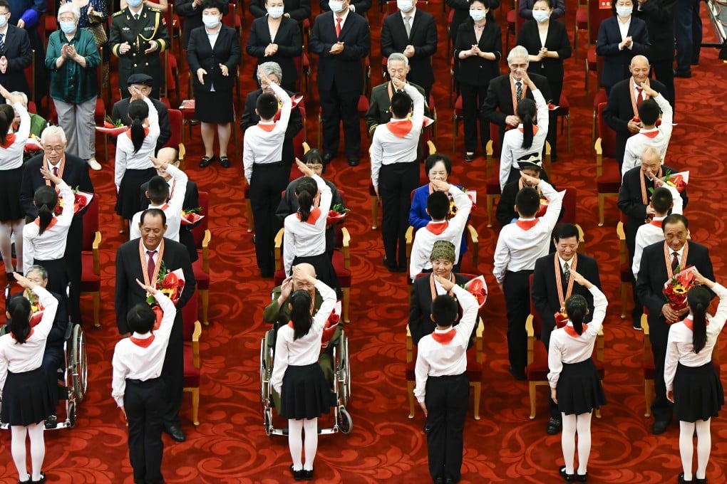 Children present flowers to the medal recipients and salute them during the ceremony at the Great Hall of the People in Beijing on Tuesday. Photo: Xinhua