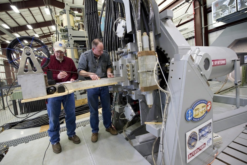 Workers take measurements after a successful test firing of an electromagnetic rail gun prototype launcher at a facility in Virginia, US. File photo: US Navy/AP