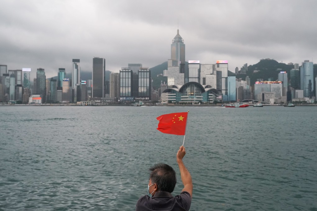 A man holds the national flag up against the Hong Kong skyline on Thursday. Photo: Felix Wong