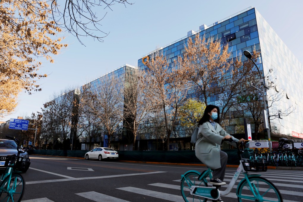 A woman rides a bike past the Beijing headquarters of Didi Chuxing. Photo: Reuters