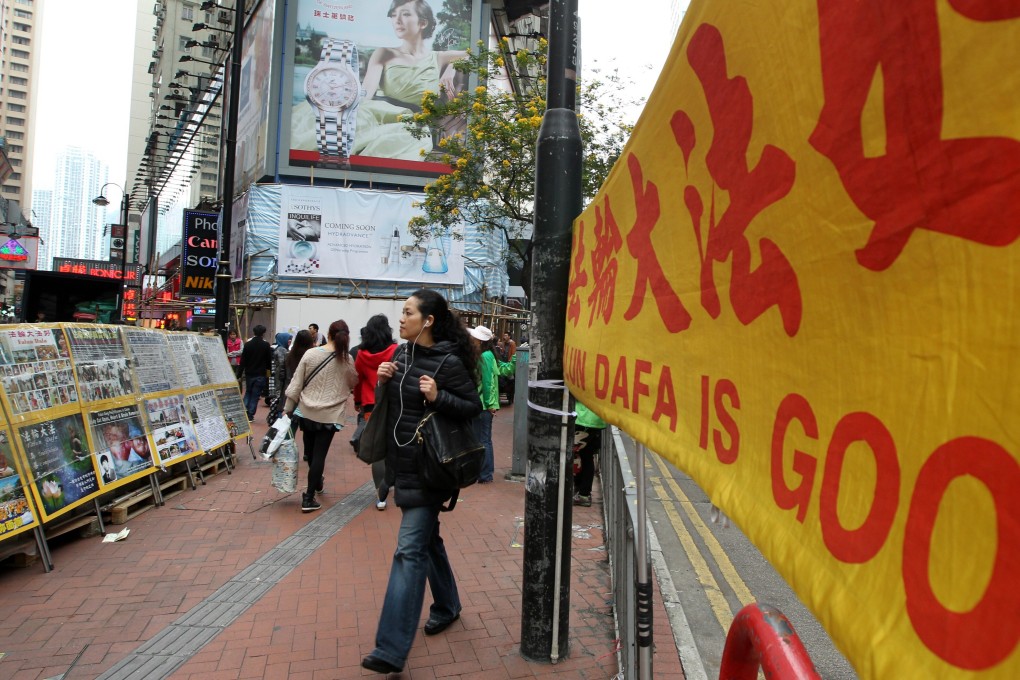 A woman walks past a display set up by the Falun Gong on a street corner in Causeway Bay in 2013. Photo: Felix Wong