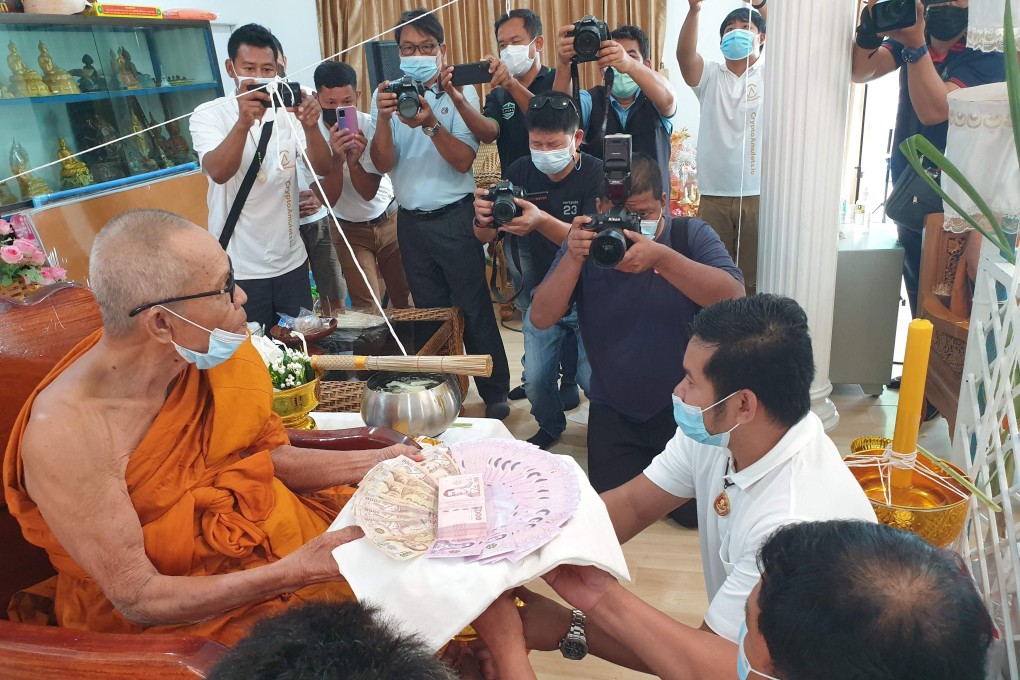 Buddhist abbot Luang Pu Heng receives a donation during a blessing ceremony for the digital amulets bearing an image of his face at the Wat Pattana Thammaram temple in Surin. Photo: Daye Chan/Ekkaphong Khemthong via AFP