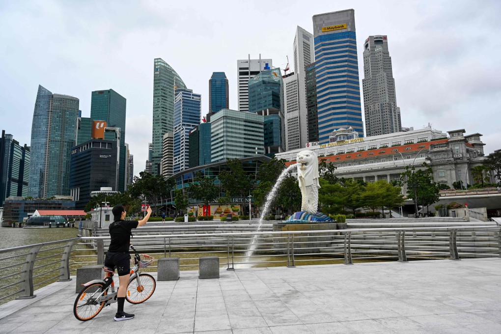 A cyclist takes a photo in front of the Merlion statue in Singapore. Photo: AFP