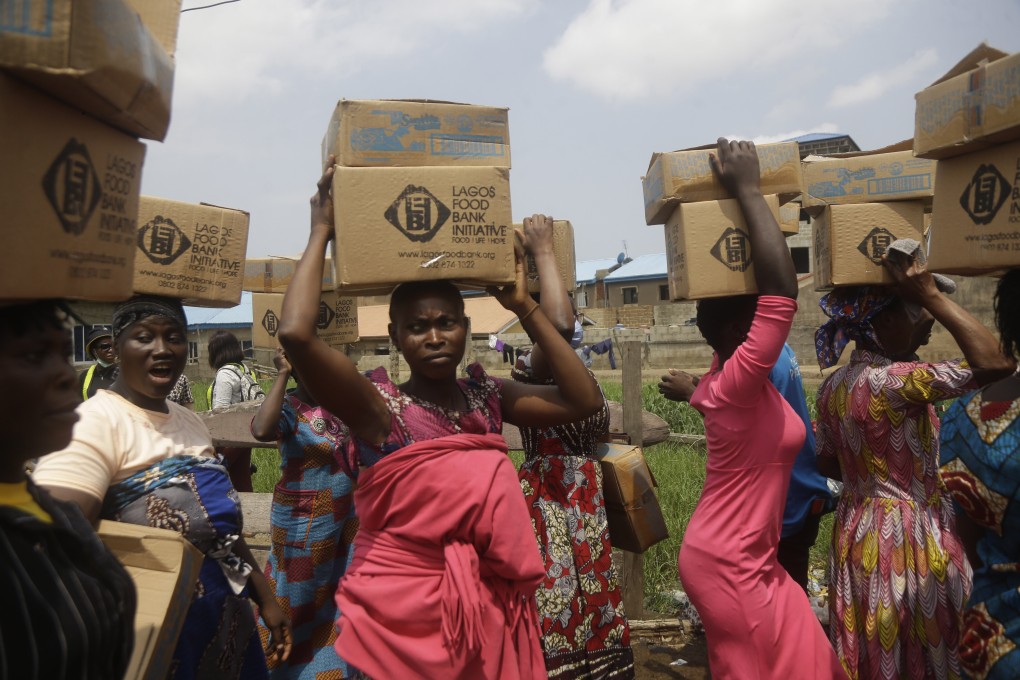 Slum dwellers in Nigeria carry food parcels distributed by a non-profit initiative committed to fighting hunger. Photo: AP