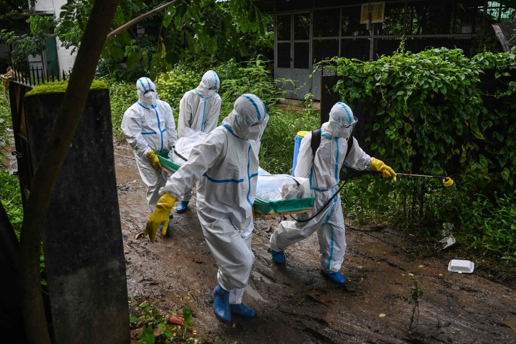 Volunteers wearing personal protective equipment carry the body of a Covid-19 casualty to a cemetery in Yangon. Photo: AFP