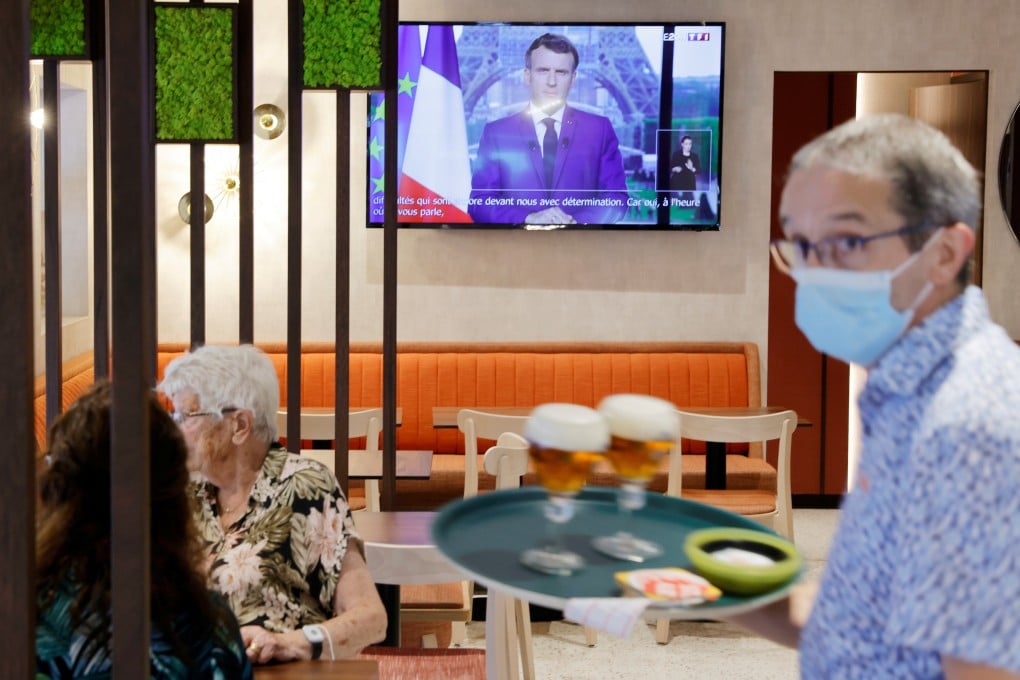 A waiter serves beer in a pub in Cambrai as French President Emmanuel Macron, on TV, addresses the nation about the state of the coronavirus in the country. Photo: Reuters