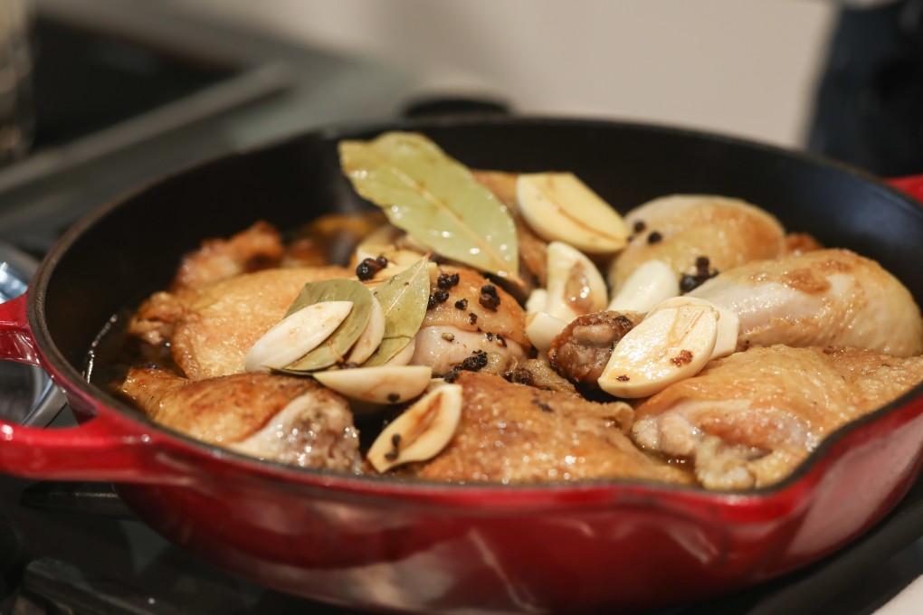 Chicken adobo simmers in a pan. Photo: Jonathan Wong