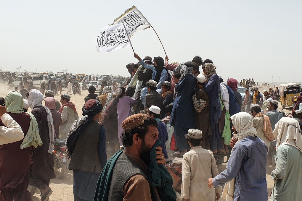 People wave a Taliban flag as they drive through the Pakistani border town of Chaman on Wednesday after the group said it captured the Afghan side of the border crossing of Spin Boldak along the frontier with Pakistan. Photo: AFP