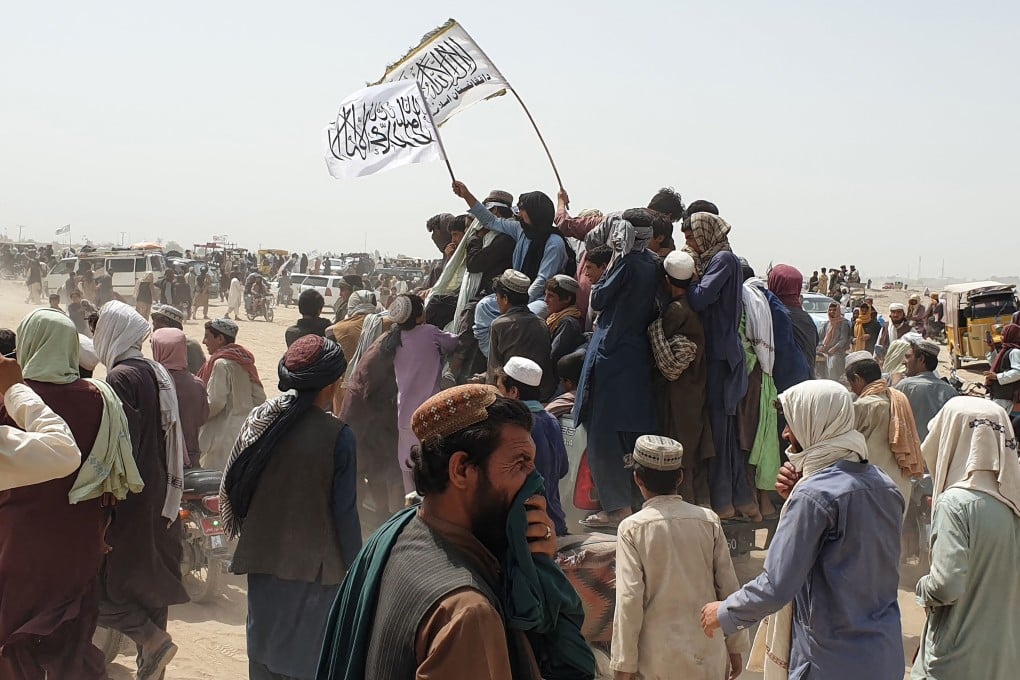 People wave a Taliban flag as they drive through the Pakistani border town of Chaman on Wednesday after the group said it captured the Afghan side of the border crossing of Spin Boldak along the frontier with Pakistan. Photo: AFP