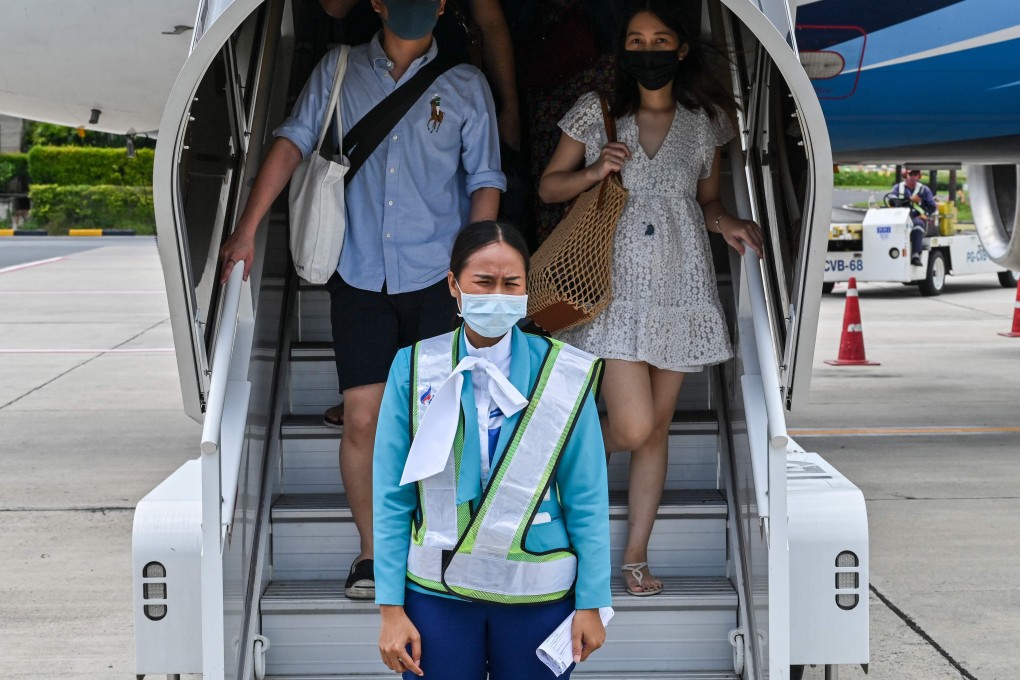 Tourists wearing face masks disembark after arriving at Koh Samui in Thailand. Photo: AFP