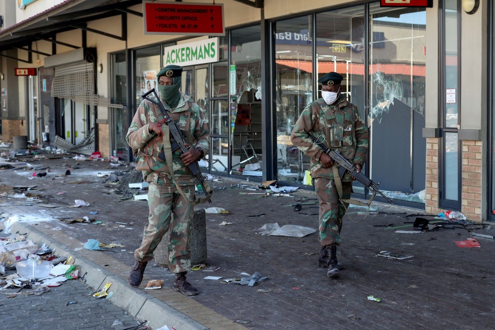 Troops patrol past looted shops in Soweto, South Africa. Photo: Reuters