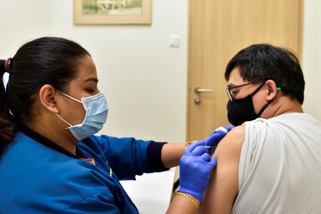 A nurse at a Singaporean vaccine administers a vaccine to a male patient. Photo: Reuters