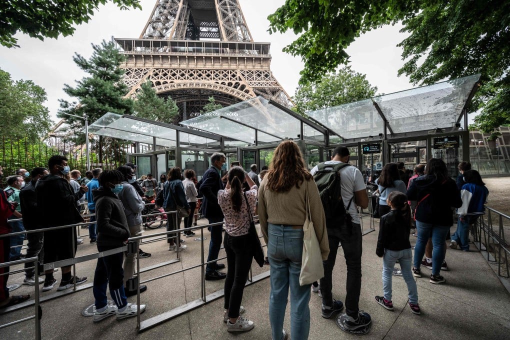 Visitors wait in line as they arrive to visit the Eiffel Tower in Paris on Friday. The French capital city attraction reopened to visitors on Friday, after nine months of shutdown caused by the Covid pandemic. Photo: AFP