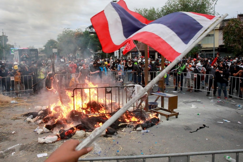 A protester waves the Thai flag as mock body bags, representing coronavirus casualties, are burnt during an anti-government demonstration in Bangkok on Sunday. Photo: Reuters