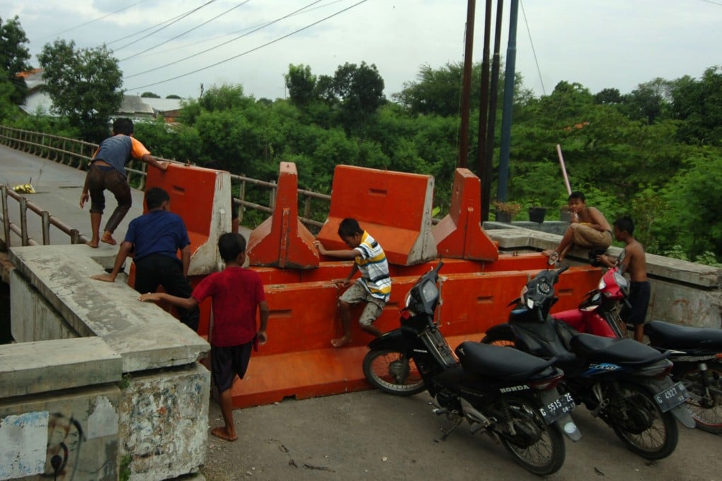 Children in Central Java Province play on barriers placed as part of movement restrictions amid surging Covid-19 cases in Indonesia. Photo: Reuters