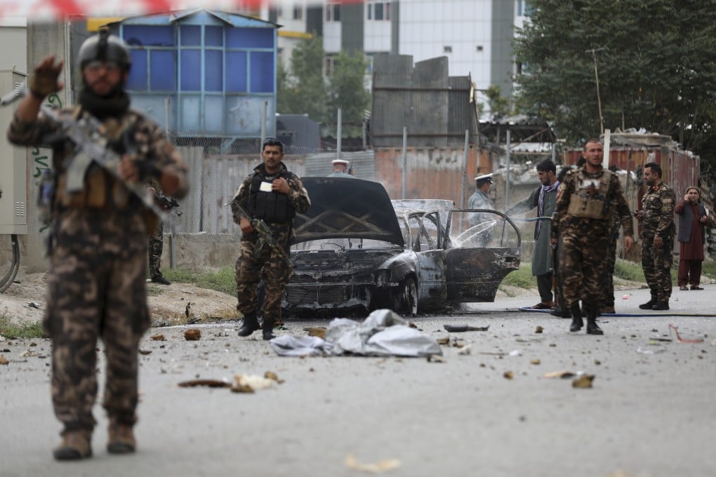 Security personnel inspect a damaged vehicle which was firing rockets in Kabul, Afghanistan. Photo: AP