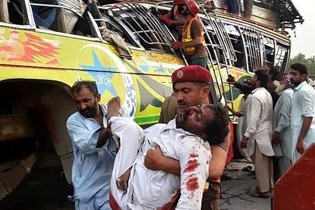 A security official carries a man injured in a bus accident near Dera Ghazi Khan in Pakistan on Monday. Photo: AFP