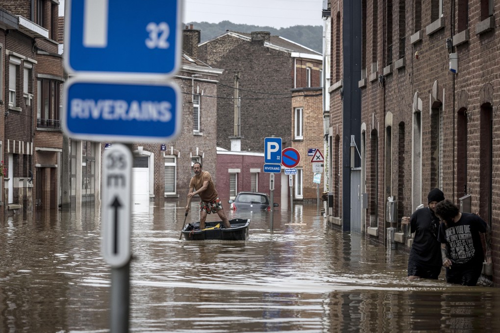 A man rows a boat down a residential street after flooding in Angleur, Belgium. There are many factors for flooding, but a warming atmosphere makes extreme weather more likely and frequent the world over. Photo: AP