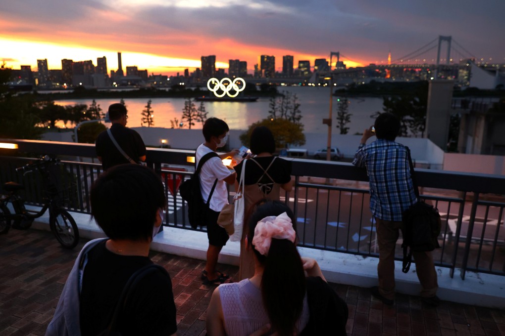 A person takes a photo of the Olympic Rings in front of the Tokyo skyline. Photo: Reuters