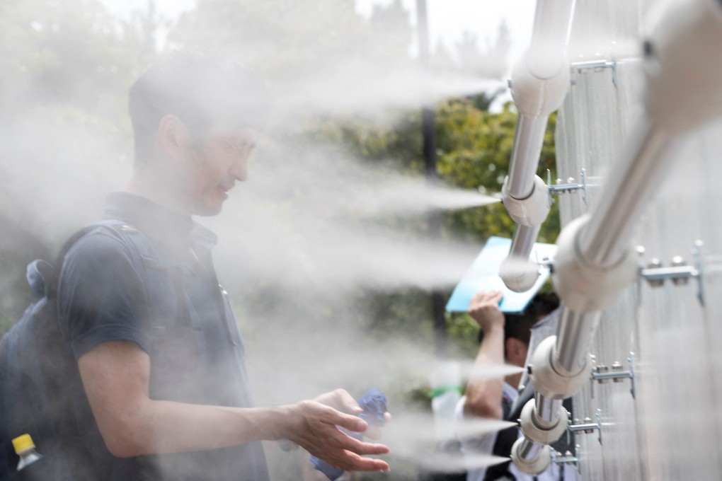 A man cools off at a mist station at Shiokaze Park in Tokyo during a beach volleyball test event. Photo: AFP
