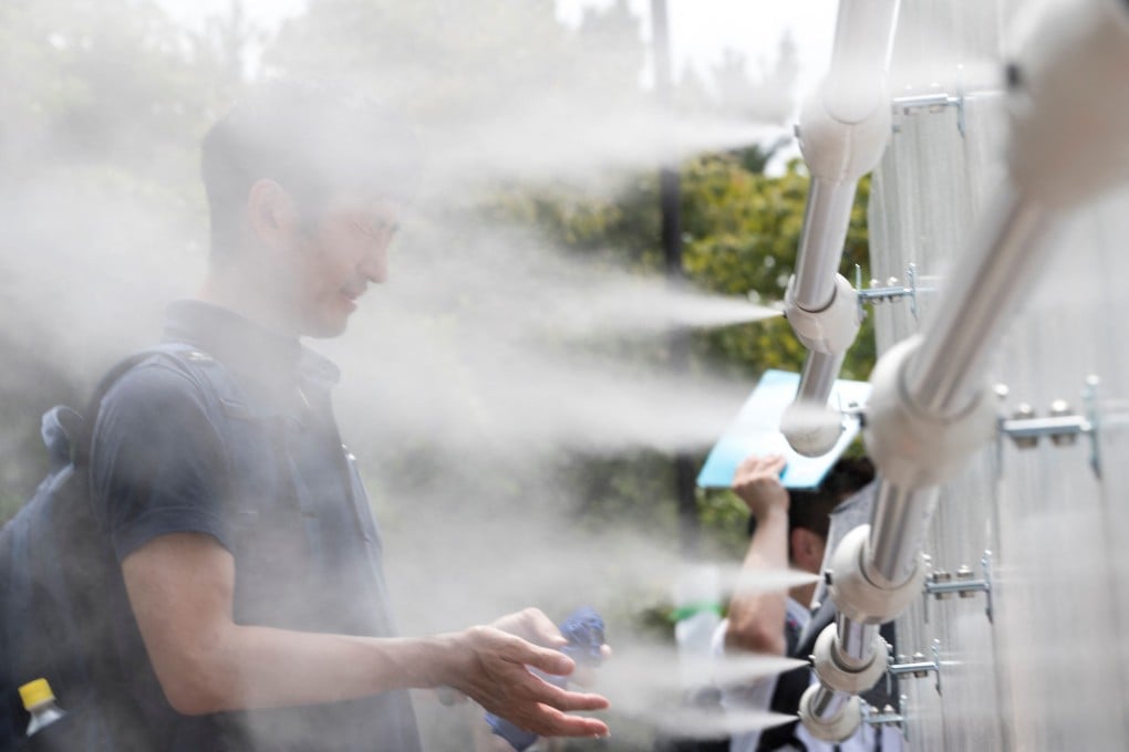 A man cools off at a mist station at Shiokaze Park in Tokyo during a beach volleyball test event. Photo: AFP