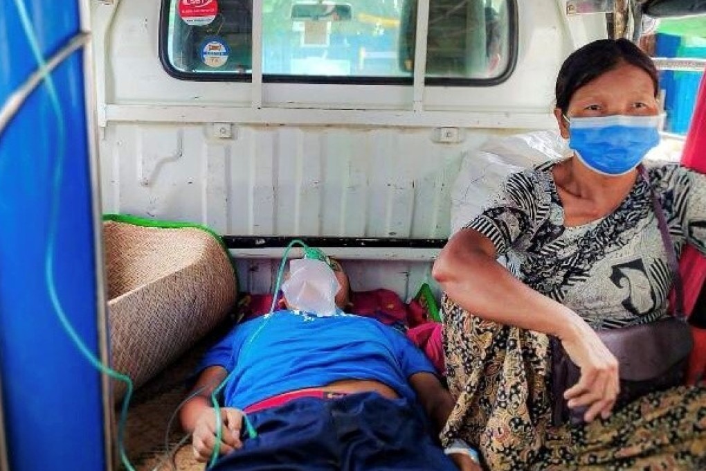 A relative sits with a coronavirus patient who is being taken to a hospital in the town of Kale, as Myanmar battles a deadly uptick in cases. Photo: Reuters